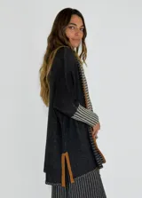 Saco azul de tejido de punto con rayas horizontales en tonos grises y detalles en rojo. Tiene corte holgado, mangas 3/4 y bolsillos laterales.