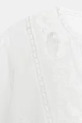 Camisa blanca de algodón con escote en pico, mangas por debajo del codo y detalles de bordados y encaje a tono en el pecho y las mangas.
