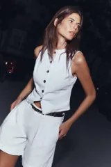 Shorts blancos de tiro alto con pinzas delanteras y bolsillos laterales. Incluye un cinturón fino negro con hebilla de cadena dorada.