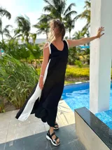 Vestido largo negro con panel lateral blanco, escote en V en la espalda y corte holgado.