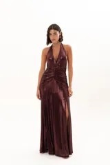 Vestido largo de fiesta en tejido brillante color bordó, con escote halter profundo, detalle de frunces en la cintura y tajo lateral en la falda.
