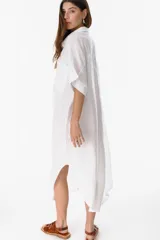 Camisola larga blanca de lino con botones de nácar y bolsillos delanteros.