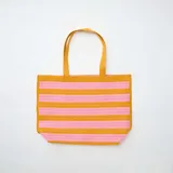 Bolso grande estilo cabás a rayas horizontales en tonos amarillo y rosado, con asas dobles de hombro.