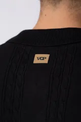 Camisa de punto de manga corta con cuello tipo bowling y cierre frontal de botones. Presenta un diseño texturizado con franjas verticales y detalles de contraste en blanco en los bordes de las mangas.