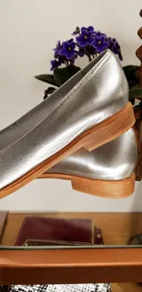 Mocasines de cuero plateado con acabado texturado, diseño clásico con costuras visibles y vira de suela natural cosida. Cuenta con taco plano de 2 cm y plantilla anatómica.