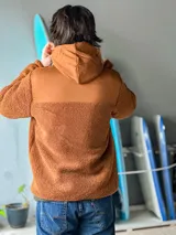 Campera de corderito de manga larga y cierre frontal, con diseño en bloques de color azul y negro. Cuenta con capucha y bolsillos laterales, además de detalles estampados con la marca y la frase 'boardbrand made for riders'.
