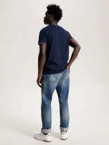 Remera azul marino de algodón con corte slim, cuello redondo y mangas cortas con ribete rojo y blanco. Logo de Tommy Hilfiger bordado en el pecho.