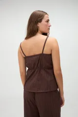 Top de pijama blanco confeccionado en algodón, con tirantes finos, escote recto y aberturas frontales con lazos ajustables.