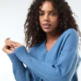 Sweater de punto en color azul, con cuello en pico y diseño de manga larga con puños acanalados.
