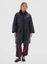 Tapado largo hasta las rodillas, color marrón, con vivos en color crema y cuello de pana. Tiene bolsillos delanteros, cierre frontal con botones a presión y cordón en la cintura para ajustar.