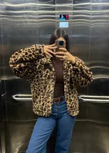 Campera de piel sintética con estampado animal print de leopardo, corte holgado, cuello alto y cierre frontal completo.