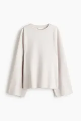 Buzo oversized color beige claro de punto interlock pesado, con cuello redondo y mangas largas amplias.