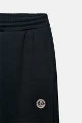 Pantalón tipo jogger de tiro medio con cintura elástica ajustable mediante cordones. Presenta un diseño de pierna recta, bolsillos laterales ocultos en las costuras y un detalle metálico con el logo ZA en la parte superior.