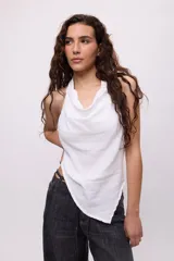 Top de algodón color blanco con cuello buche y bajo irregular en punta. Presenta un diseño sin mangas y espalda semidescubierta.