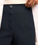 Short de sastrería color rosado, de tiro alto con detalles de pinzas frontales y cartera abotonada con cuatro botones revestidos. Presenta diseño recto y estructurado.
