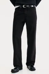 Jean de cinco bolsillos en denim negro, con cintura estándar y cierre de botón. Presenta un corte relajado desde la cadera hasta el bajo, con pierna recta y amplia a partir del muslo.