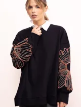 Buzo de algodón color negro con cuello redondo, mangas largas y bordado floral XL en color cobre en las mangas. Presenta un diseño holgado y cómodo.