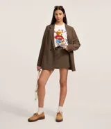 Short pollera de sastrería color marrón, de corte recto y estilo alfatado, con cierre tradicional y bolsillos. Incluye cinturón desmontable de poliuretano.