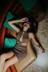 Minivestido dorado de tejido de punto con lurex, cuello halter con abertura central, cut-outs laterales y espalda descubierta.