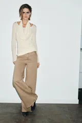 Camiseta de manga larga color crudo con cuello redondo y detalle de top halter superpuesto en el mismo tejido. Presenta un diseño de doble capa con caída drapeada en el frente.