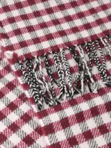 Bufanda de tejido suave con diseño de cuadros vichy en blanco y negro, terminada con flecos en los extremos.