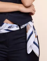 Pashmina de satén estampado en tonos blanco, azul marino y dorado, con diseño clásico de cadenas y detalles ecuestres.
