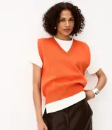 Chaleco de tricot naranja con escote en V profundo, hombreras internas y terminaciones acanaladas en cuello, sisas y bajo.