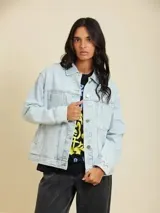 Campera de jean azul claro con bolsillos frontales con solapa, cierre de botones metálicos y corte oversize.
