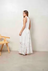 Vestido largo beige con cuello halter y detalle de broderie calado en el dobladillo inferior.