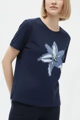 Remera de manga corta color azul marino con cuello redondo y estampado frontal de una flor en tonos celestes y blancos.