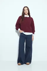 Sweater negro de tejido texturizado con líneas horizontales en relieve, de silueta levemente holgada y hombros caídos.