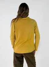 Remera de manga larga con cuello polo y cierre frontal de dos botones. Presenta un diseño de corte recto y acabado desgastado en las costuras.