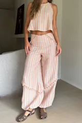Pantalón babucha de lino a rayas, con diseño de pierna amplia, corte relajado y detalles de flecos en los bolsillos y botamangas.