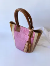 Bolso matero de cuero color fucsia y marrón con textura croco, doble asa de mano marrón y detalle de borlas de cuero marrón.