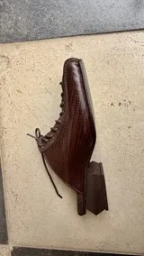 Zapatos destalonados de cuero en combinación marrón y negro con textura de cocodrilo, cordones negros, puntera cuadrada y taco geométrico de madera.