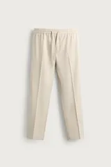 Pantalón regular fit color beige con cintura elástica ajustable con cordón y bolsillos frontales.