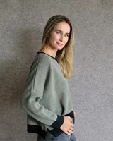 Buzo de punto con diseño de rayas verticales en tonos tostado y beige, con una estrella grande en la espalda y terminaciones en color verde oliva. Presenta un corte holgado y mangas anchas.