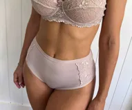 Bombacha de tiro alto confeccionada en lycra color rosado, con paneles laterales de encaje floral a tono.