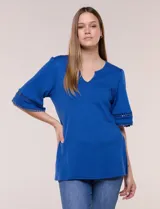 Remera de algodón azul con escote redondo y pequeña abertura central en V. Cuenta con mangas de largo intermedio decoradas con una inserción horizontal de puntilla calada y tajos laterales en el ruedo.