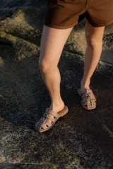 Sandalias de cuero con diseño de tiras entrelazadas, estilo jaula, con suela plana y cierre de hebilla lateral.