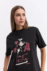 Remera de corte oversize color beige, con cuello redondo y mangas cortas. Presenta un estampado frontal con motivos florales abstractos y la frase 'Ciao Bella' en tonos bordó y crema.