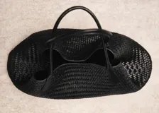 Bolso grande de diseño trenzado en color negro, con asas cortas para hombro y cierre de botón magnético.