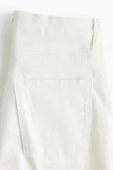 Jean de tiro alto con corte acampanado desde la rodilla, confeccionado en denim con leve elasticidad. Presenta diseño clásico de cinco bolsillos, cierre frontal con cremallera y botón.