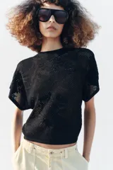 Top de punto pointelle color negro, con cuello redondo y mangas cortas anchas de diseño holgado.