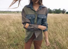 Camisa de estilo patchwork confeccionada en una combinación de tejidos de tweed con diferentes patrones de cuadros y texturas en tonos verdes, marrones y azules. Presenta cuello clásico, cierre frontal con botones, dos bolsillos frontales con solapa y manga larga con puños abotonados. Incluye un parche de cuero con el logo de la marca en la manga.