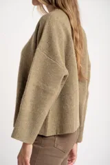 Sweater de lana de corte oversize, con cuello redondo y mangas largas con puños acanalados. Diseño de tejido liso en tono neutro.