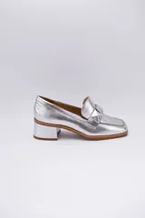 Mocasines plateados de cuero con aplique geométrico al tono y taco cuadrado.