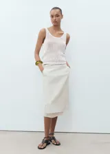 Top de crochet color blanco, sin mangas, con cuello escotado y tirantes anchos.