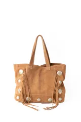 Bolso estilo shopper de gamuza color marrón, con diseño artesanal que incluye flecos laterales y apliques de tachas metálicas circulares. Cuenta con doble asa de hombro y costuras a la vista.