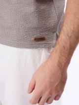 Remera polo de manga corta en tejido cloqué color gris, con cuello camisero y cierre frontal de botones.